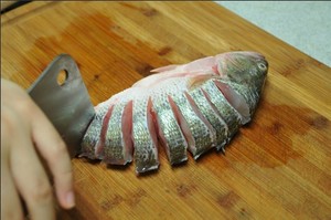 將鱸魚(yú)清洗干凈，從脊椎處切斷至腹部，腹部保留1cm左右不要切斷。