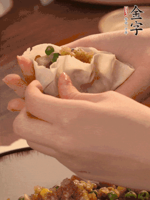 取一大勺餡料放進(jìn)餃子皮里，用大拇指按住頂部餡料，再用虎口掐出形狀。
